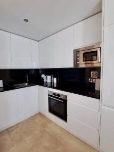 una cucina con mobili bianchi e un forno a microonde di Luxury stay, resort - style pools & spa - prime a Gibilterra