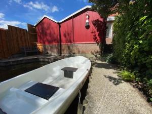 a boat sitting in the water next to a red building at Ferienhuus En Söten in Bedekaspel
