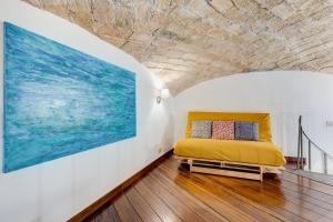 una camera da letto con un letto giallo e un grande dipinto di Casa Valentina - Oasi di tranquillità e stile a Testaccio a Roma Altre 37 foto
