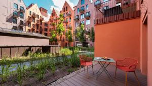 a balcony with two chairs and a table and some buildings at Flatbook - City Centre Granaria II & SPA in Gdańsk