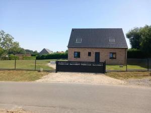 a house with a black roof and a fence at maison de campagne in Bourthes