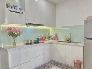 une cuisine avec des placards blancs et un vase de fleurs dans l'établissement Cố Đô Homestay, à Thôn Văn Dương