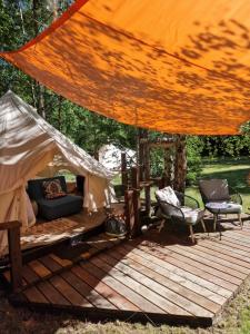 a tent with a couch and chairs on a wooden deck at Glamping Štôla Lesný duch in Vyšné Hágy +24 photos