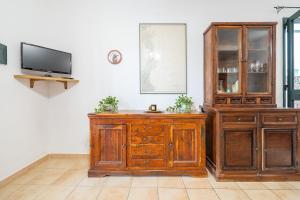 a living room with a tv and a wooden cabinet at AffittaSardegna - Domo Pineta in Santa Lucia
