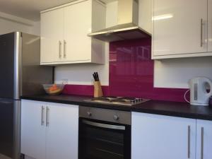 a kitchen with white cabinets and a stove top oven at Warm & Cozy 3-Bed Apartment at Kexgill in Middlesbrough