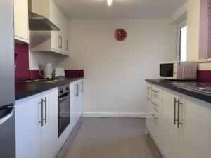 a small kitchen with white cabinets and a microwave at Warm & Cozy 3-Bed Apartment at Kexgill in Middlesbrough
