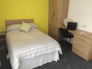 a bedroom with a bed and a desk with a laptop at Warm & Cozy 3-Bed Apartment at Kexgill in Middlesbrough