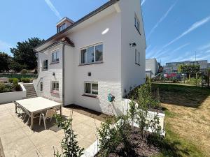 Una casa blanca con una mesa delante de ella. en Villa Strada - Koksijde, en Koksijde