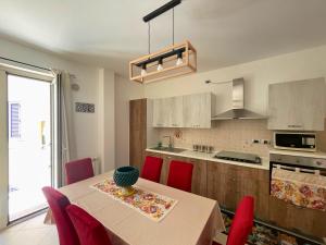 una cocina con mesa con sillas rojas y una cocina con armarios blancos en I Love Sicily, en Spadafora