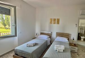 two beds in a white room with a window at B&BPodere1149 in Villafranca +5 photos