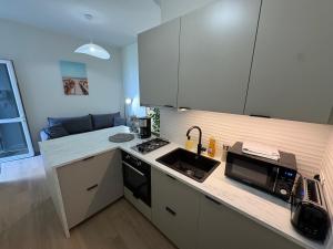 a kitchen with white cabinets and a sink and a microwave at TiBZH, Vannes centre, Entrée privative in Vannes