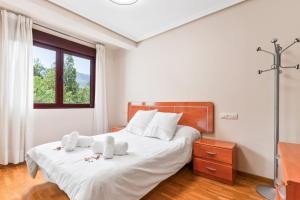 ein Schlafzimmer mit einem Bett mit weißer Bettwäsche und einem Fenster in der Unterkunft Apartamento Avenida del Mar in Oviedo