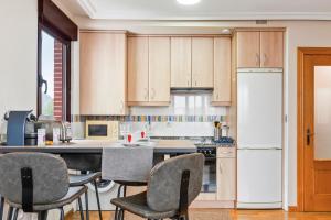 eine Küche mit Holzschränken und einem weißen Kühlschrank in der Unterkunft Apartamento Avenida del Mar in Oviedo