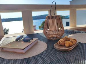 a table with a plate of donuts and a book and a lamp at Villa Paris in Nečujam