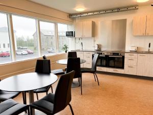 a kitchen with tables and chairs in a room at Eiðar - Hostel in Egilsstaðir