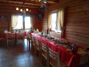 a long dining room with red tables and chairs at Romo sodyba in Trakai