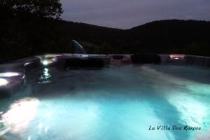 a hot tub filled with blue water at night at La Villa Des Raspes - Séjour Spa - Adult Only in Viala-du-Tarn