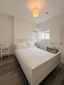 a white bedroom with a large bed and a window at Nelson Road North in Great Yarmouth
