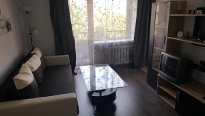 a living room with a couch and a tv and a table at L.E.C. Travel Apartments Ventspils in Ventspils