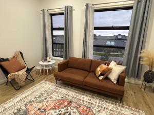 a living room with a couch and two windows at Urban Pause - Doreen in Doreen
