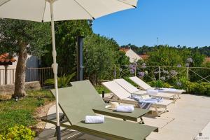 a row of green and white chairs and an umbrella at Hedera Estate Villa Hedera XVIII in Mlini