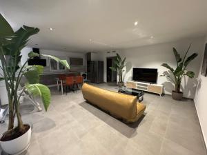 sala de estar con sofá amarillo y TV en Villa Oasis, en Albacete