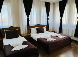two beds in a hotel room with white sheets at Hotel Antika in Prizren
