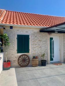 a brick house with a green door and a wheel at Vranac Country house Šibenik in Donje Polje