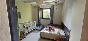 a small room with a crib and a small bedroom at Maison familiale in Pleslin-Trigavou