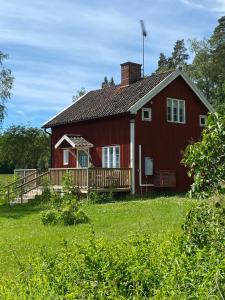 a red house with a porch and a deck at Elsas koja in Vittinge