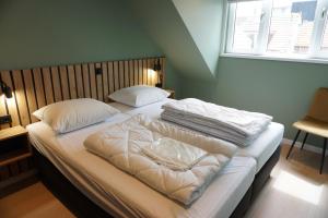 a bedroom with two beds with white sheets and a window at Guesthouse Breskens in Breskens