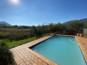 a swimming pool on a patio with mountains in the background at Sani Lodge & Cottages in Sani Pass