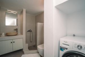 a bathroom with a toilet and a sink and a washing machine at Anemopetra in Apollonia +20 photos