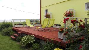 two yellow chairs sitting on a wooden deck with flowers at Domek Piaski Nad Morzem in Krynica Morska