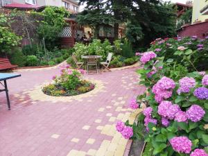 a patio with pink flowers and a table and chairs at Domek Piaski Nad Morzem in Krynica Morska +6 photos