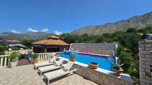 a swimming pool with lounge chairs and a house at Villa Maslina in Petrača