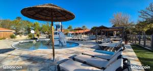 a pool with lounge chairs and an umbrella at Mobil Home Premium Camping Mayotte 5 CLIM TV LV R096 in Biscarrosse
