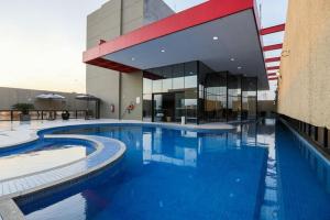 a large swimming pool in front of a building at Apartamento no Hotel Radisson Belém in Belém