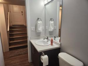 a bathroom with a sink and a mirror and a toilet at Springfield Kensington in Saskatoon