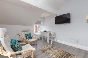 a living room with chairs and a tv and a table at Lytham St Annes Luxury Apartment - No 3 Tides Reach in Lytham St Annes