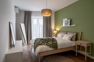 a bedroom with a bed with a green wall at Vidalis Suites in Cluj-Napoca