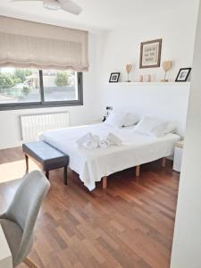 a white bedroom with two beds and a chair at Villa Serenità by Prolocal in Cunit
