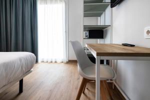 a bedroom with a bed and a desk and a bed and a table at Hotel Calella by Beatriz Hoteles in Calella