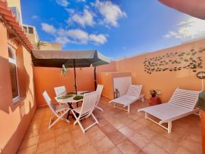 un patio con tavolo, sedie e ombrellone di Casa del Gato a Caleta De Fuste