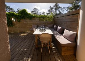 a patio with a table and a bench on a deck at Le Lodge du Cap Ferret in Cap-Ferret