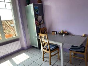 une cuisine avec une table, des chaises et un réfrigérateur dans l'établissement La chambre Terra Cotta, à La Celle-sous-Gouzon