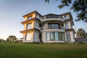 a large white house on a grassy field at Къща за гости Гардения in Kamburovo