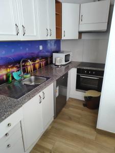 Una cocina con gabinetes blancos y un fregadero. en Apartmani Prestige, en Baška Voda