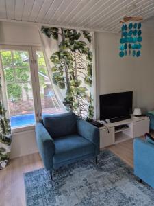 a living room with a blue chair and a television at Villa Mosahiisi Charming Poolside Getaway in Helsinki