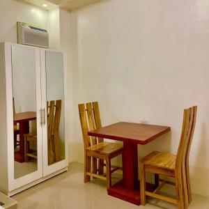 a dining room with a table and chairs and a cabinet at Iwa Hotel in Tagbilaran City +3 photos